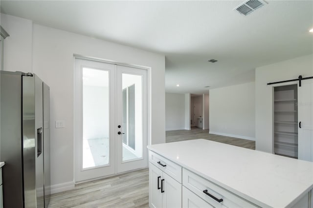 kitchen with french doors, visible vents, a barn door, light wood-style floors, and white cabinetry