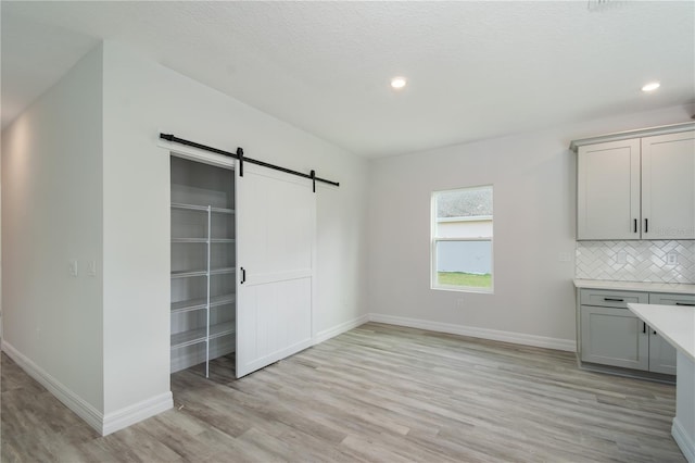 interior space featuring light wood-style floors, a barn door, and baseboards