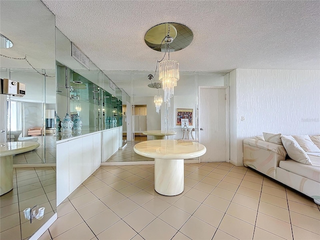 interior space featuring an inviting chandelier, a textured ceiling, light tile patterned floors, and hanging light fixtures