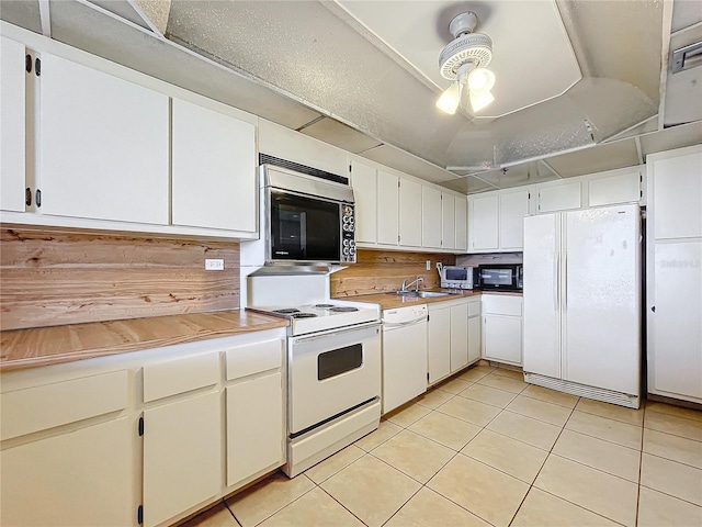 kitchen with white appliances, white cabinets, sink, and light tile patterned floors