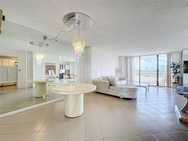 tiled living room with a notable chandelier, a textured ceiling, and a wall of windows