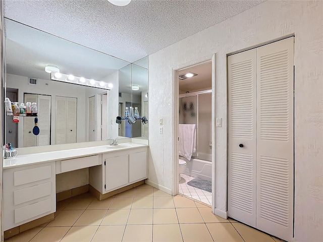 full bathroom with a textured ceiling, tile patterned flooring, toilet, enclosed tub / shower combo, and vanity