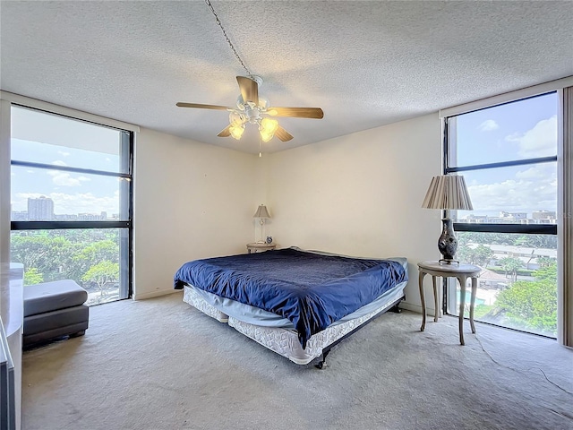 carpeted bedroom with a textured ceiling, ceiling fan, and multiple windows