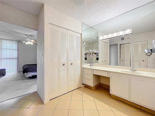 bathroom with tile patterned floors, vanity, a textured ceiling, and ceiling fan