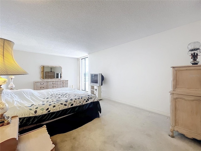 bedroom with a textured ceiling and light colored carpet