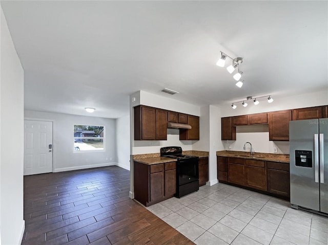 kitchen with sink, stainless steel refrigerator with ice dispenser, electric range, light stone counters, and dark brown cabinetry