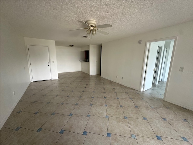 empty room with ceiling fan, light tile patterned floors, and a textured ceiling