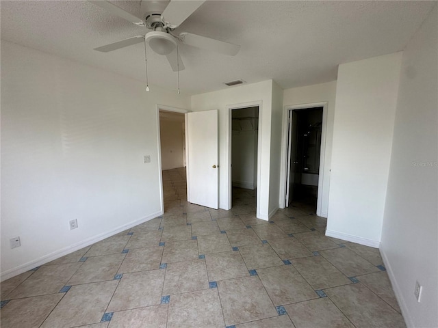 unfurnished bedroom with ceiling fan, a spacious closet, a textured ceiling, and a closet