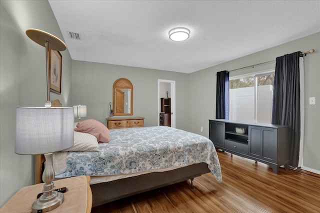 bedroom featuring a textured ceiling and light hardwood / wood-style flooring