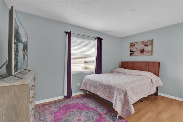 bedroom with a textured ceiling and light hardwood / wood-style flooring