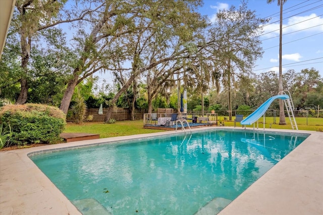 view of pool with a water slide and a yard