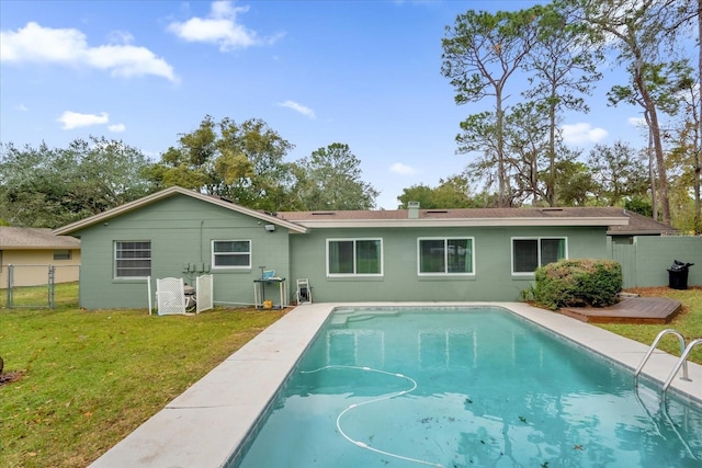 back of property with a yard and a fenced in pool