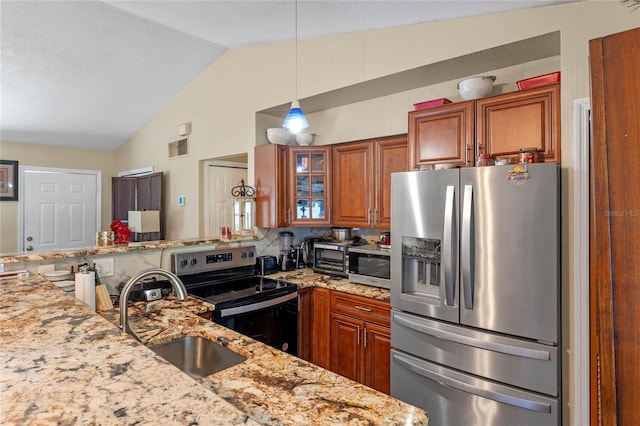 kitchen featuring lofted ceiling, sink, light stone countertops, appliances with stainless steel finishes, and decorative light fixtures