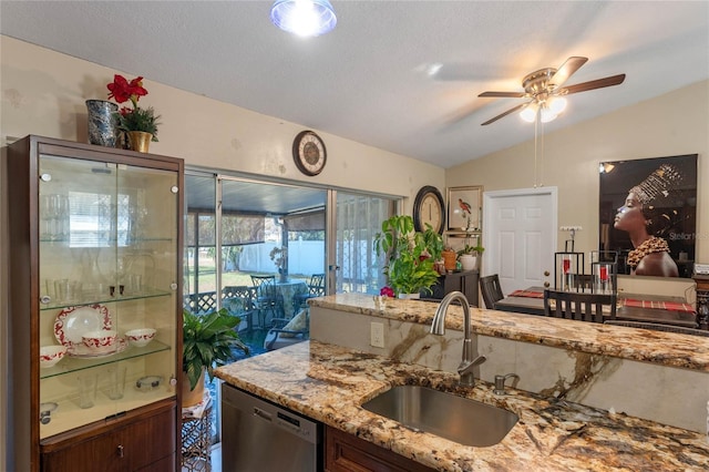 kitchen featuring ceiling fan, sink, light stone counters, stainless steel dishwasher, and vaulted ceiling