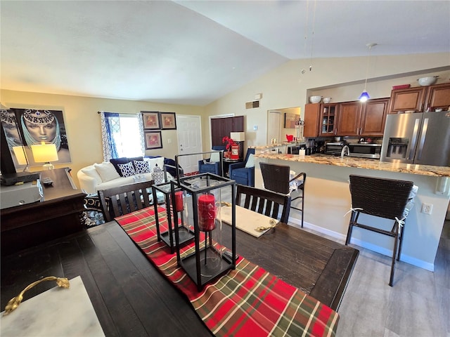 dining area with hardwood / wood-style flooring and vaulted ceiling