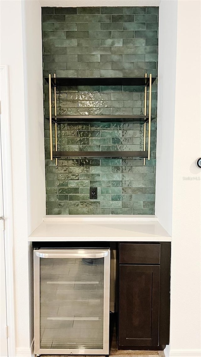 bar with wine cooler and dark brown cabinetry