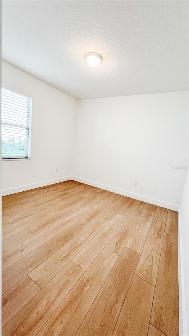 spare room with a textured ceiling and hardwood / wood-style floors