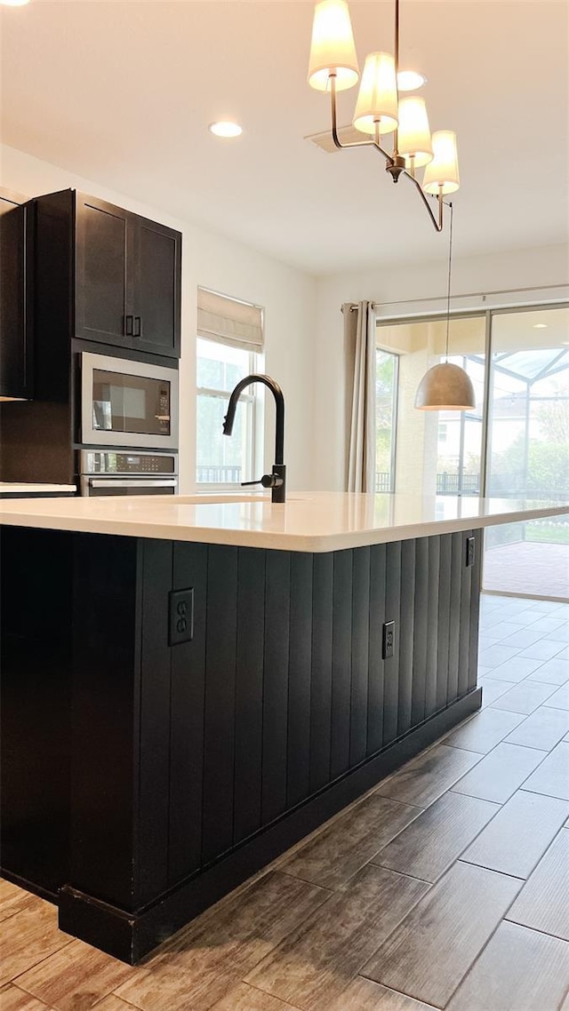 kitchen with built in microwave, oven, a chandelier, pendant lighting, and sink