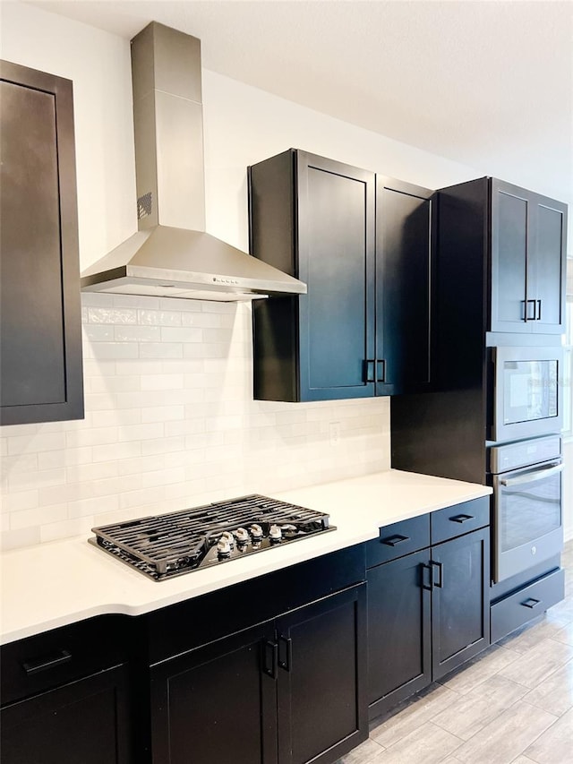 kitchen featuring tasteful backsplash, wall chimney exhaust hood, and white appliances