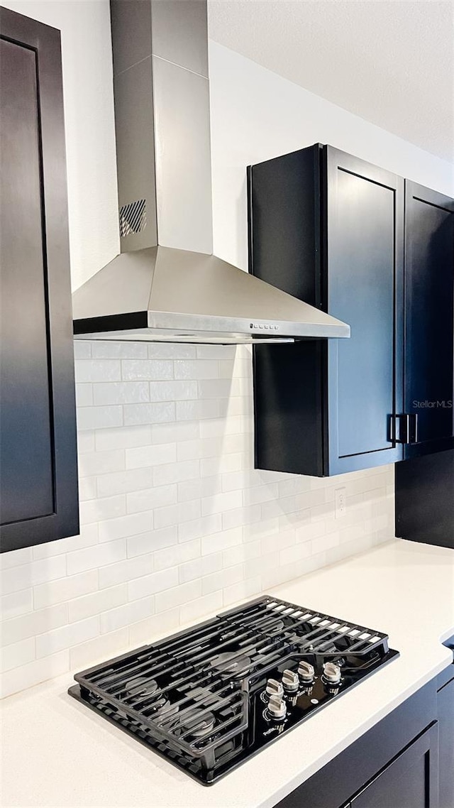 kitchen featuring black gas cooktop, decorative backsplash, and wall chimney exhaust hood