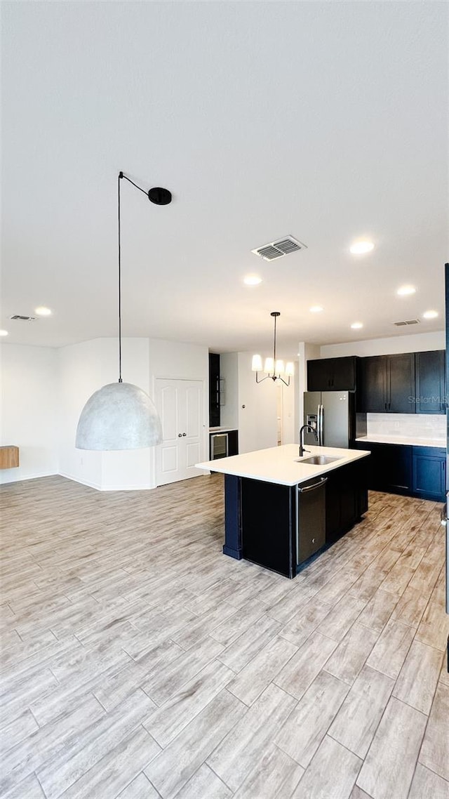 kitchen featuring decorative light fixtures, stainless steel fridge with ice dispenser, a center island with sink, and black dishwasher