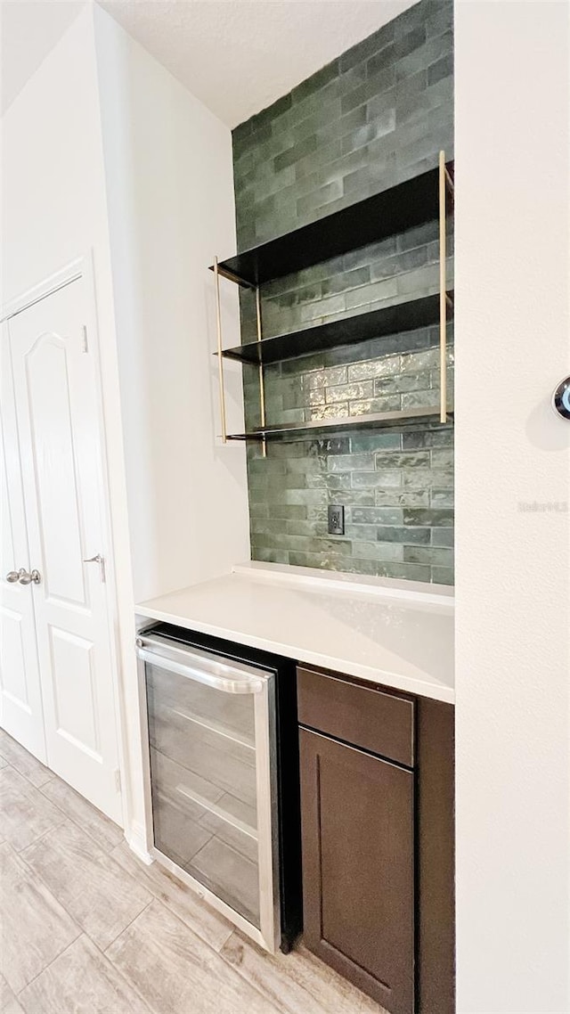 bar with wine cooler and dark brown cabinetry