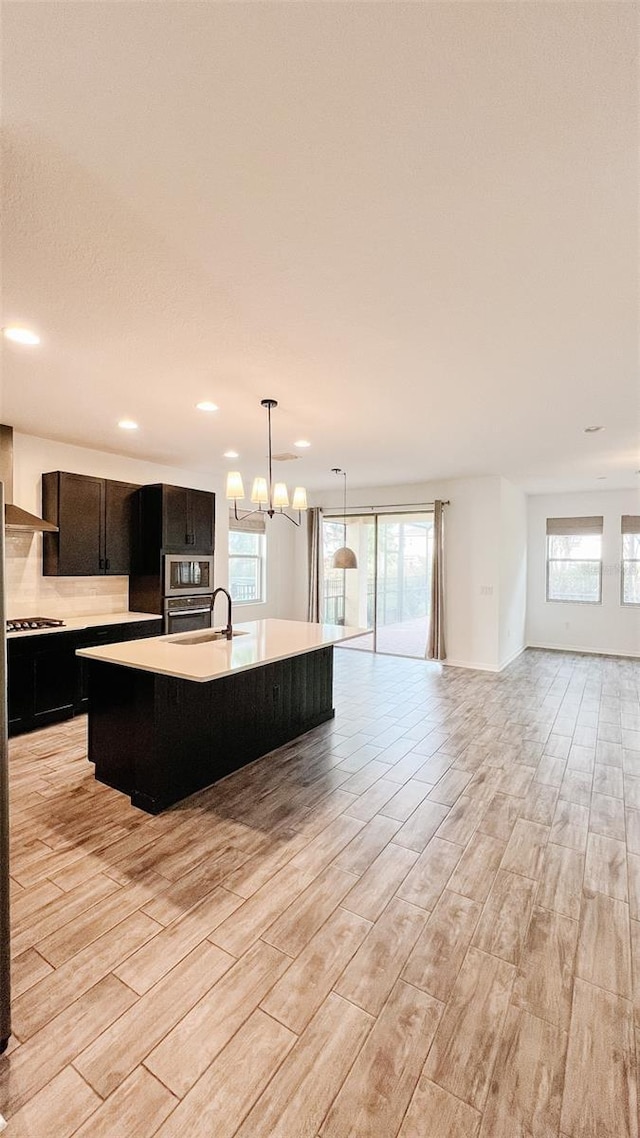 kitchen featuring hanging light fixtures, a kitchen island with sink, appliances with stainless steel finishes, and sink