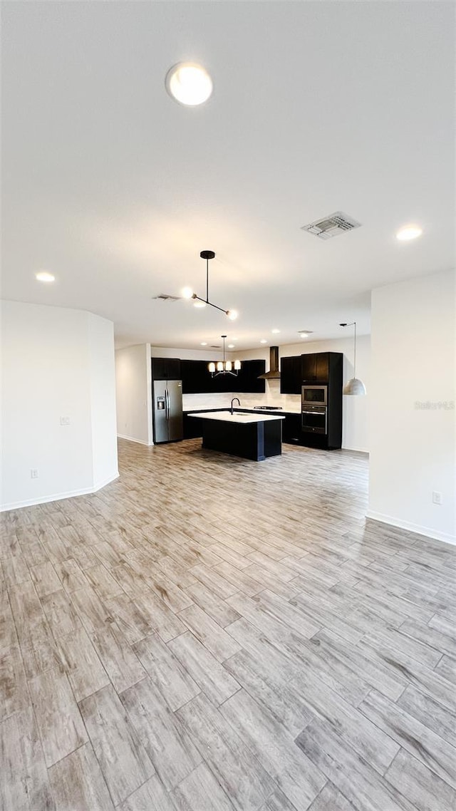 kitchen featuring stainless steel fridge with ice dispenser, a chandelier, pendant lighting, and a center island