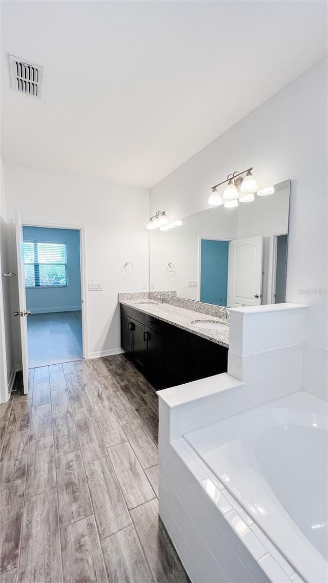 bathroom featuring vanity and a relaxing tiled tub