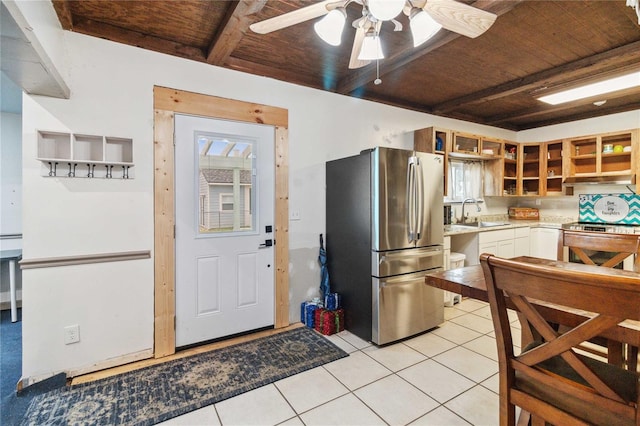 kitchen featuring light tile patterned floors, stainless steel appliances, light countertops, wooden ceiling, and beamed ceiling