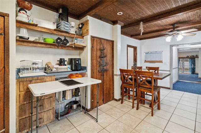 interior space featuring baseboards, a ceiling fan, wood ceiling, beamed ceiling, and light tile patterned flooring