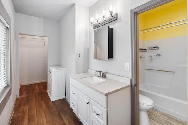 full bathroom with toilet, a walk in closet, wood finished floors, and vanity