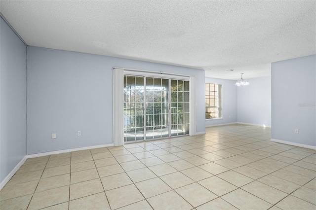 spare room featuring light tile patterned floors, a textured ceiling, and a chandelier