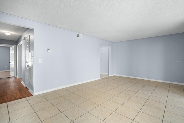 spare room with light tile patterned flooring and a textured ceiling