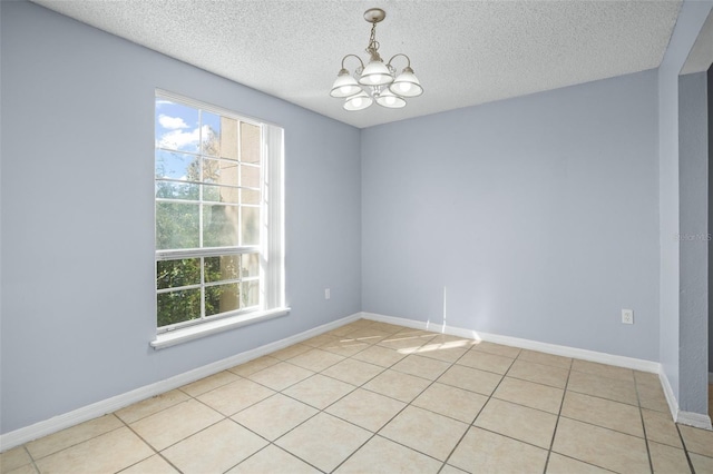 tiled empty room with a textured ceiling and an inviting chandelier