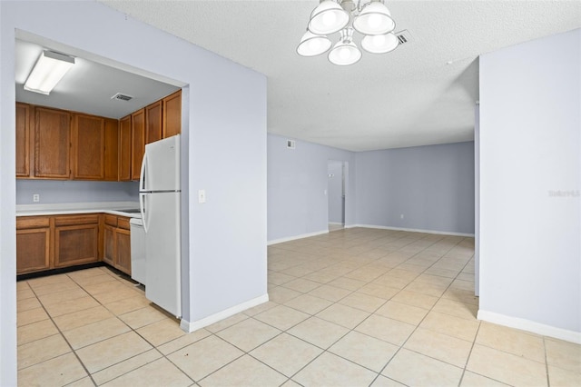 kitchen with light tile patterned floors, white fridge, a chandelier, and a textured ceiling