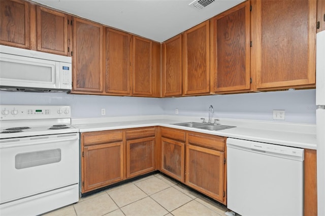 kitchen featuring light tile patterned flooring, white appliances, and sink