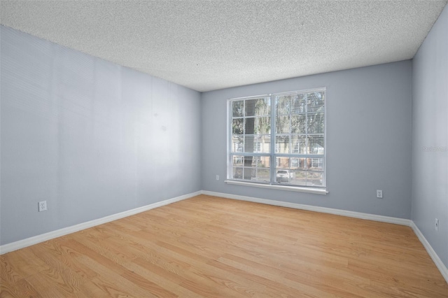 spare room with a textured ceiling and light hardwood / wood-style floors