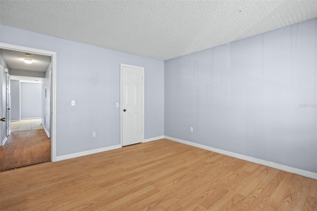 unfurnished room with a textured ceiling and light hardwood / wood-style flooring