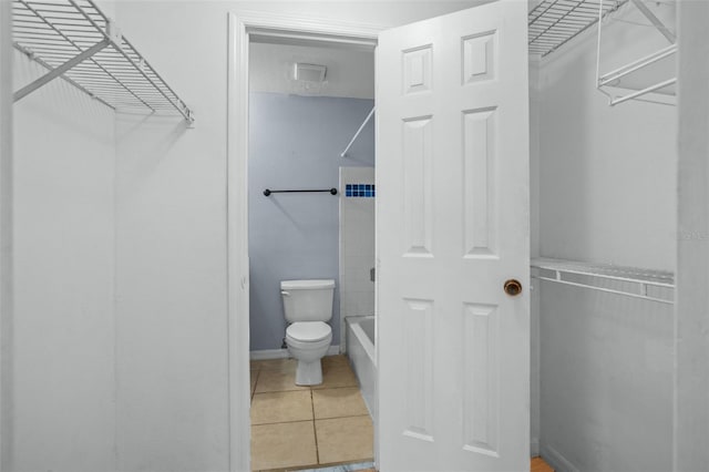 bathroom with toilet, tile patterned floors, and washtub / shower combination