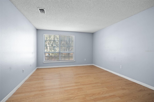 empty room featuring a textured ceiling and light hardwood / wood-style floors