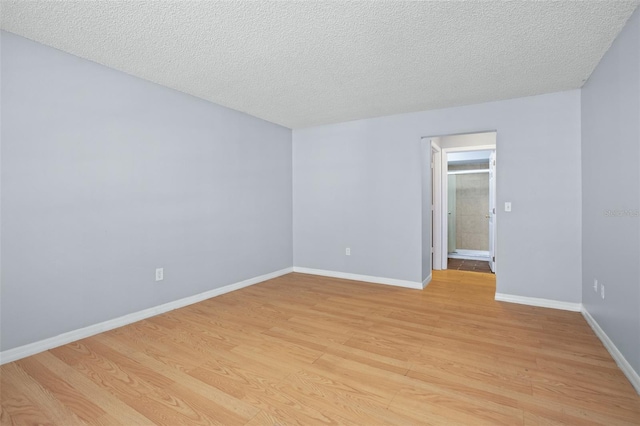 unfurnished room with light wood-type flooring and a textured ceiling