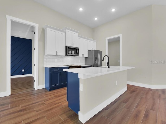 kitchen featuring a center island with sink, blue cabinetry, appliances with stainless steel finishes, and white cabinets