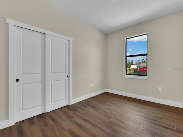 unfurnished bedroom featuring a closet and dark hardwood / wood-style flooring