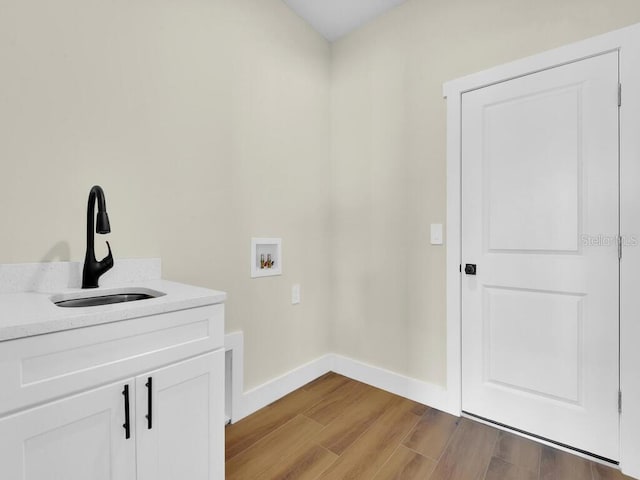 washroom featuring sink, washer hookup, cabinets, and light hardwood / wood-style floors