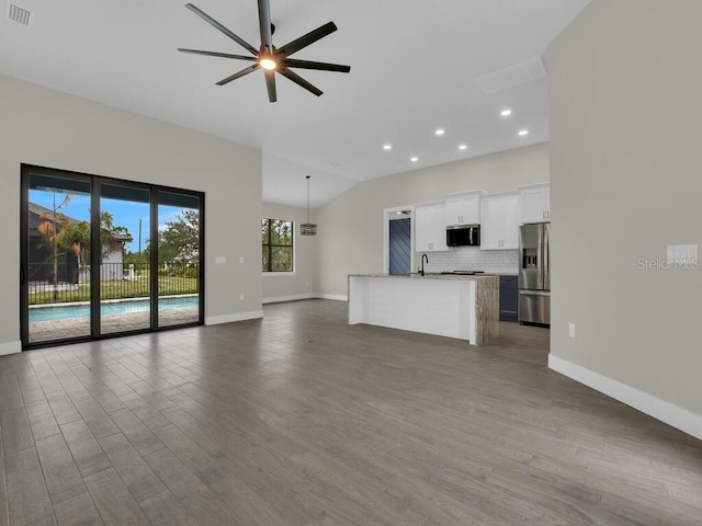 unfurnished living room featuring baseboards, visible vents, lofted ceiling, dark wood-style flooring, and ceiling fan