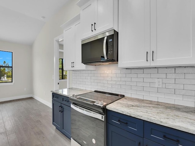 kitchen with blue cabinets, tasteful backsplash, white cabinetry, appliances with stainless steel finishes, and light wood finished floors