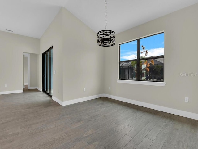 unfurnished room featuring baseboards, wood finished floors, and a chandelier