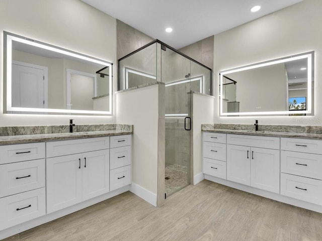 bathroom featuring recessed lighting, two vanities, wood finished floors, and a shower stall