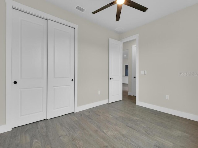 unfurnished bedroom featuring visible vents, wood finished floors, a closet, baseboards, and ceiling fan